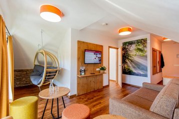 Moderner Wohnbereich mit Sofa, Hängesessel, Holzboden und TV-Wand im Hotel Engel im Schwarzwald