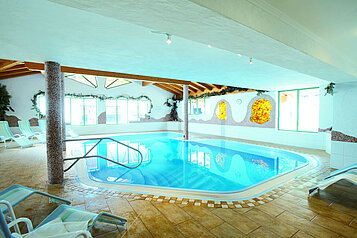 Schwimmbad mit viel Tageslicht und Liegen zum entspannen im Familienhotel Landgut Furtherwirt in Tirol.