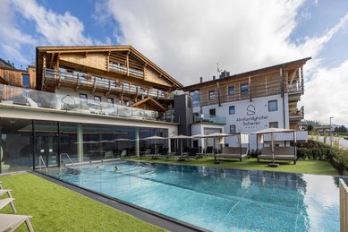 Außenansicht des Familienhotels Almfamilyhotel Scherer mit beheiztem Pool und Liegebereich in sonniger Lage in Osttirol.