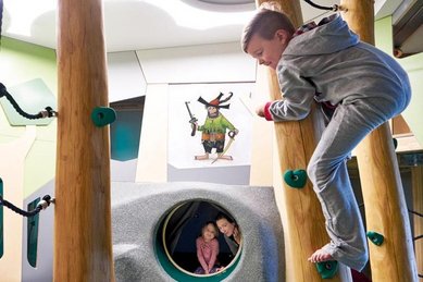 Junge klettert in der Räuberhöhle des Familienhotels Amiamo im Salzburger Land.