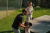 Vater und Mutter spielen gemeinsam mit ihrer kleinen Tochter Tischtennis im Familienhotel Engel Gourmet & Spa.