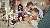 Familie sitzt am gedeckten Tisch im Restaurant des Familienhotels Amiamo im Salzburger Land und isst ihr Abendessen