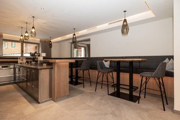 Moderne Hotelbar mit hohen Sitzplätzen und stilvollen Lampen im Familienhotel Oberkarteis.