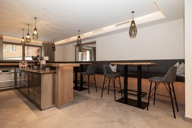Moderne Hotelbar mit hohen Sitzplätzen und stilvollen Lampen im Familienhotel Oberkarteis.
