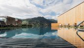 Zwei moderne Liegenbereiche am Außenpool mit Blick auf die Berge des Familienhotels Scherer.