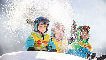 Kinder toben im Schnee im Familienurlaub in Vorarlberg.