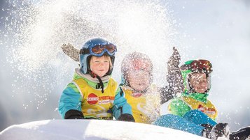 Kinder toben im Schnee im Familienurlaub in Vorarlberg.