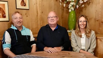 Gastgeberteam des Familienhotels Bavaria sitzt lächelnd in einer gemütlichen Stube.