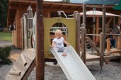 Ein kleines Mädchen auf der Rutsche auf dem Spielplatz am Familienhotel Habachklause im Salzburger Land 