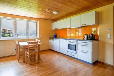 Helle Küche mit Esstisch und großen Fenstern im Familienhotel Sonne Bezau.