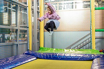 Mädchen springt auf dem Trampolin im Abenteuerland des Familienhotels Sonnenpark im Sauerland