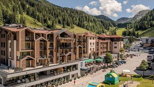 Familienhotel Zauchenseehof im Sommer mit Blick auf das modernisierte Gebäude und den angrenzenden Spielbereich vor der Bergkulisse.