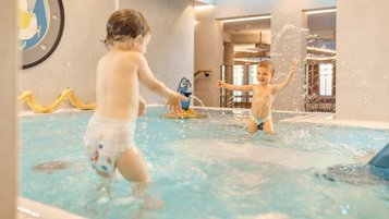 Zwei Kleinkinder planschen im Babybecken des Alpenhotels Kindl in Tirol.