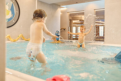 Zwei Kleinkinder planschen im Babybecken des Alpenhotels Kindl in Tirol.