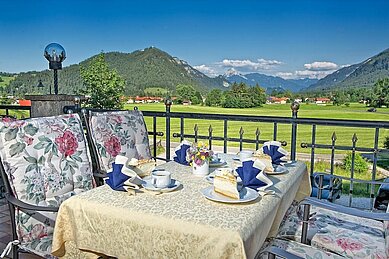 Blick auf einen gedeckten Tisch auf der Terrasse des Familienhotels Bavaria im Allgäu mit Blick auf die Berge