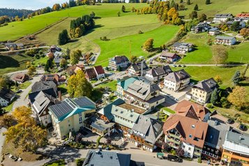 Luftaufnahme des Hotel Engel im Schwarzwald eingebettet in ein Dorf mit grünen Wiesen und Schwarzwaldhügeln