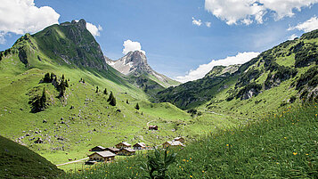 Wandern im Vorarlberg: Blick auf das Alpe Laguz im großen Walsertal. Kleines Bergdorf im Hintergrund der Berge.