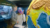 Vater und Sohn betrachten eine Weltkugel im Mensch und Natur Museum in München.