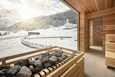 Aussicht auf die wundervolle Winterlandschaft von der Sauna durch das große Panoramafenster im Familienhotel Bella Vista in Südtirol.