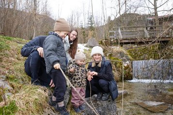 Familie beim Walderlebnis am Bachlauf in der Natur rund um das Familienhotel Das Bayrischzell