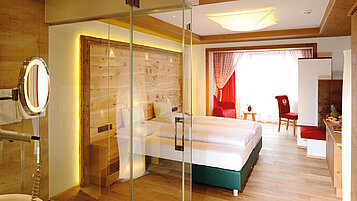 Schönes Doppelzimmer Superior mit mit Blick ins Badezimmer durch Glastüren im Familienhotel Das Kaltschmid in Seefeld in Tirol.