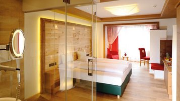 Schönes Doppelzimmer Superior mit mit Blick ins Badezimmer durch Glastüren im Familienhotel Das Kaltschmid in Seefeld in Tirol.