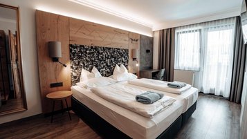 Schönes Doppelzimmer Superior mit mit Blick ins Badezimmer durch Glastüren im Familienhotel Das Kaltschmid in Seefeld in Tirol.
