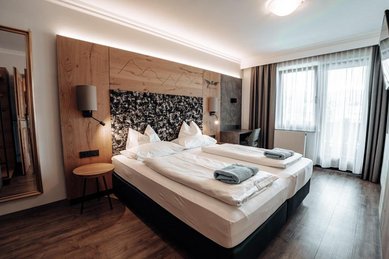 Schönes Doppelzimmer Superior mit mit Blick ins Badezimmer durch Glastüren im Familienhotel Das Kaltschmid in Seefeld in Tirol.