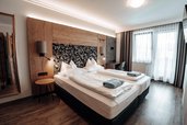 Schönes Doppelzimmer Superior mit mit Blick ins Badezimmer durch Glastüren im Familienhotel Das Kaltschmid in Seefeld in Tirol.
