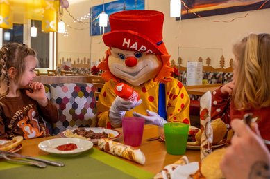 Clown Happy besucht die Kinder beim Essen im Restaurant.