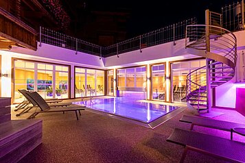 Outdoor-Pool mit lilafarbener Ambienten-Beleuchtung im Familienhotel Galtenberg Family & Wellness Resort in Tirol.