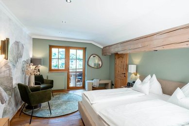 Helles Familienzimmer mit Doppelbett, Sitzecke und Zugang zum Balkon im Familienhotel Post.