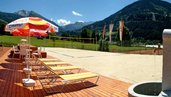 Großer Volleyballplatz mit Liegen und Sonnenschirmen auf dem Gelände vom Familienhotel Sonngastein in Bad Gastein.