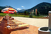 Großer Volleyballplatz mit Liegen und Sonnenschirmen auf dem Gelände vom Familienhotel Sonngastein in Bad Gastein.