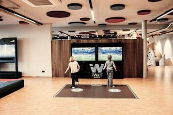 Innenbereich der Fun Company im Familienhotel Mia Alpina in Tirol mit Kindern auf einem Spielteppich iWall und großem Fernseher.