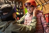 Im Skiverleih des Familienhotels Elldus im Erzgebirge hilft ein Ski-Lehrer beim Anpassen des Helms für das Kind.