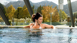 Wellness im Salzburger Land: Frau genießt entspannte Stunden im Pool mit einer herrlichen Aussicht.