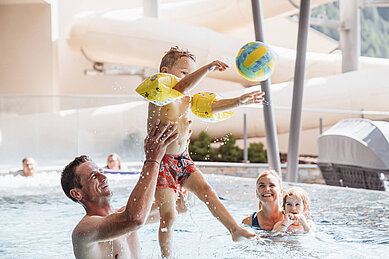 Mutter und Vater planschen gemeinsam mit ihren beiden Kindern im Familienschwimmbad im Familienhotel Huber.