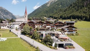 Das Familienhotel Huber von außen im Sommer. Auf dem Hotelgelände befindet sich ein Außenpool.