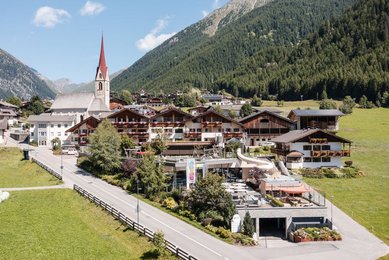 Das Familienhotel Huber von außen im Sommer. Auf dem Hotelgelände befindet sich ein Außenpool.