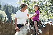 Vater sieht seinem Kind beim Ponyreiten im Familienurlaub im Mons Silva Private Luxury Chalets in Südtirol zu.