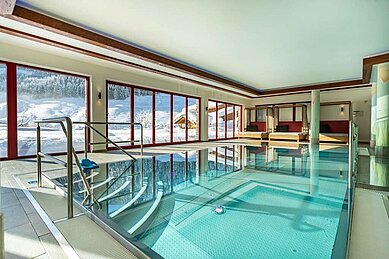 Panorama Hallenbad des Familienhotels Oberkarteis mit verschneiter Landschaft draußen.