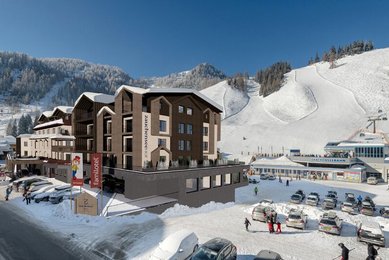 Visualisierung des Familienhotels Zauchenseehof im Winter mit direkter Lage an der Skipiste und Blick auf die Talstation der Zauchenseebahn.