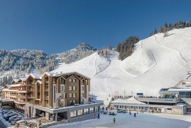 Visualisierung des Familienhotels Zauchenseehof im Winter mit direkter Lage an der Skipiste und Blick auf die Talstation der Zauchenseebahn.