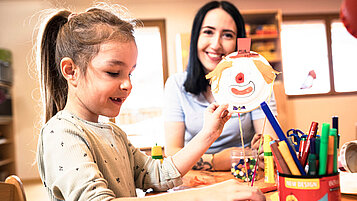 Kinderbetreuerin bastelt gemeinsam mit einem Mädchen im Happy-Club