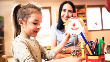 Kinderbetreuerin bastelt gemeinsam mit einem Mädchen im Happy-Club