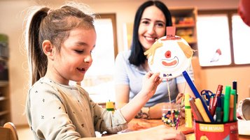 Kinderbetreuerin bastelt gemeinsam mit einem Mädchen im Happy-Club