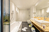 Modernes Badezimmer mit einer Badewanne und zwei Waschbecken im Familienhotel Kaiserhof an der Zugspitze.