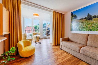 Heller Wohnbereich mit Sofa, Sesseln, Holzboden und Balkonzugang im Hotel Engel im Schwarzwald