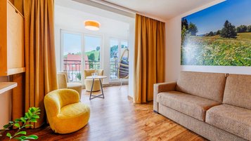 Heller Wohnbereich mit Sofa, Sesseln, Holzboden und Balkonzugang im Hotel Engel im Schwarzwald